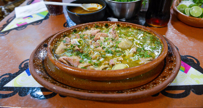 Typical dish from Guadalajara, Jalisco, called CARNE EN SU JUGO, on a handmade clay plate made in Mexico with spicy sauces on the background