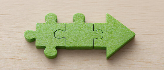 Three green jigsaw puzzle pieces assembled into an arrow shape on a wooden table, symbolizing growth, progress, strategy, path, direction, and development.