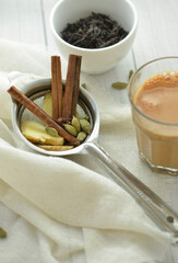 Ingredients for Indian Masala Chai or Tea. Fresh ginger, cinnamon and cardamom are placed in a tea sieve along with a hot cup of Chai. 