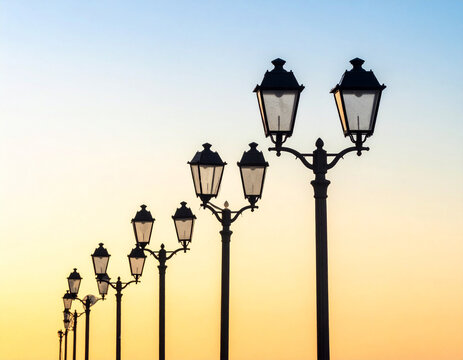 Elegant Row of Vintage Street Lamps Silhouetted Against a Soft, Gradient Sunset Sky.