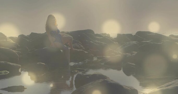 Wellness presenter shifting and dipping toes into tidepool for relaxation with animated sun flares