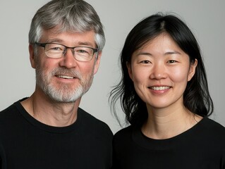 Smiling diverse professional duo in modern attire posing for a portrait with warm expressions against a neutral background