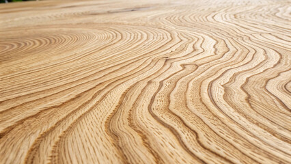 Naklejka premium Detailed wood surface with prominent grain lines creating organic curves and swirls in pale golden hardwood material.