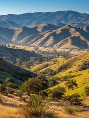 Breathtaking panoramic view of rolling hills and mountain ranges du daytime with vibrant green vegetation and clear blue sky