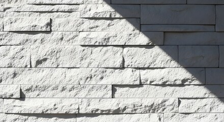 White brick wall with sunlight casting a shadow creating a geometric pattern design effect