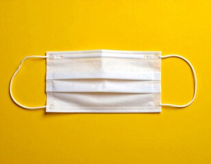 Single white protective face mask on a vibrant yellow background