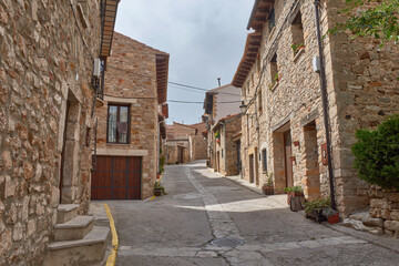 Picturesque alleys of the medieval village of Puertomingalvo, Teruel, with stone houses and flowerpots
