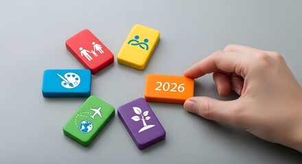 Conceptual image of strategic planning for the year 2026, with a hand placing blocks with life and business goal icons
