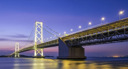 Obraz premium Modern suspension bridge at twilight. Vast steel structure spans a body of water. Illuminated towers and roadway. Coastal scenery