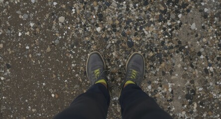 Person's shoes on a rocky and wet pebble beach, looking downwards