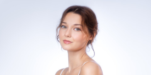 Fototapeta premium Elegant Young Woman with Natural Makeup on Soft Studio Background