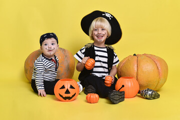 Baby and a 3-year-old boy in Halloween costumes. Small children pose on a yellow background