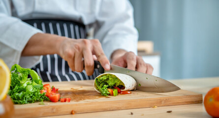 Chef is preparing a wrap with lettuce and tomatoes