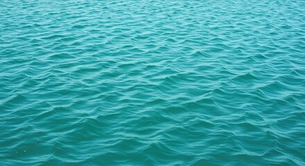 Obraz premium Vibrant turquoise ocean waves ripple gently under a bright, sunny sky, creating a serene and refreshing natural backdrop perfect for summer, travel, and relaxation themes.