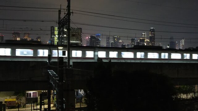 City train moving on elevated tracks at night with skyline background
