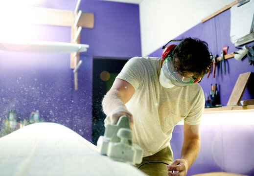 Man, workshop and foam with sanding, surfboard and creativity for skills, talent and hobby. Tools, artist and entrepreneur with craftsman for design manufacturing and custom work for artisan craft