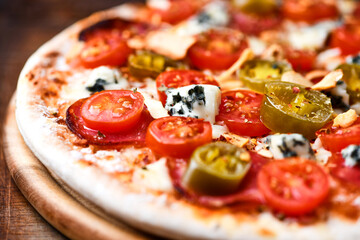Pizza with salami, jalapeno pepper, cherry tomatoes and mozzarella cheese. Soft focus.	