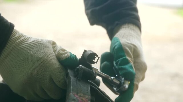 Close up of a technician hands in protective gloves meticulously unscrewing a metal nut from a vehicle component using a socket wrench during a repair or maintenance service