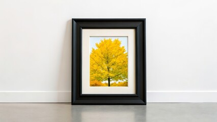 Artwork showcasing a vibrant yellow tree in a black frame against a minimalist wall and floor, highlighting autumn's beauty