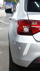 Fototapeta premium Silver car's rear quarter panel, showing a small sticker on the taillight, minor paint chips visible