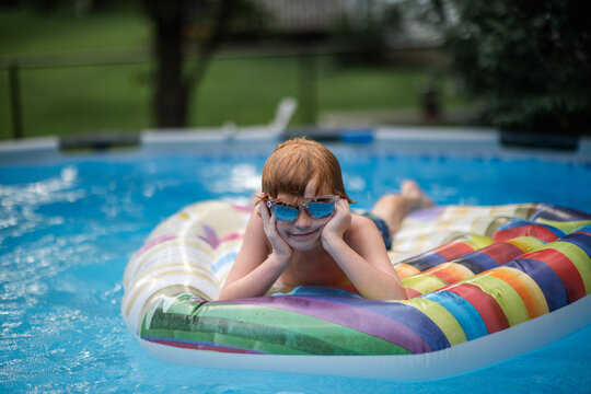 Relaxed child enjoying warm sunny day floating in backyard pool
