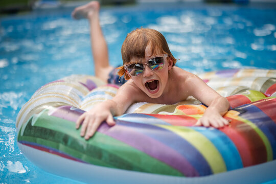 Cheerful young kid splashing around during outdoor summer holiday fun