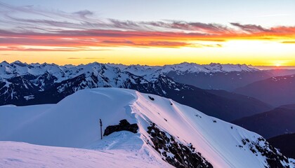 Vibrant sunset paints a snow-covered mountain range in warm hues, casting long shadows across the pristine, undulating peaks