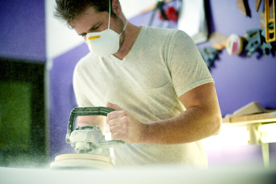 Man, tools and foam with sanding, surfboard and creativity for skills, talent and hobby. Workshop, artist and entrepreneur with craftsman for design manufacturing and custom work for artisan craft