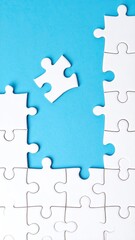 Obraz premium A single white jigsaw puzzle piece sits apart from a partially completed puzzle against a light blue background