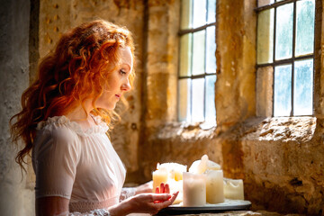 Portrait of a beautiful woman with long red hair, highlighted in the light through an old church...