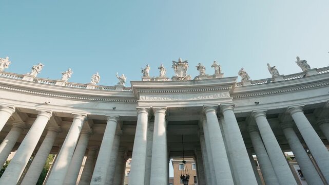 St. Peter's Square colonnade with statues and columns under clear sky in Vatican City, Rome, Italy