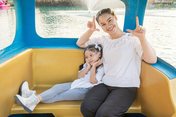 Asian mother and daughter take pictures together on a floating boat in the lake.