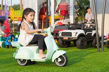 Girl are playing motorcycles, toys on the playground.