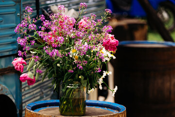 A vibrant mix of pink and purple flowers in a rustic jar, ideal for spring decor that adds charm to any space
