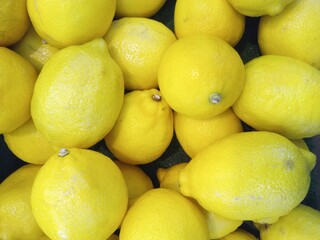 Bright lemons gathered tightly in glowing heap.