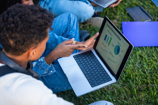 University students discussing data on laptop outdoors