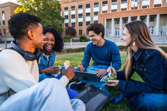 Diverse university students laughing, eating lunch on campus