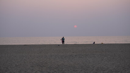 couple walking on beach and sunset
