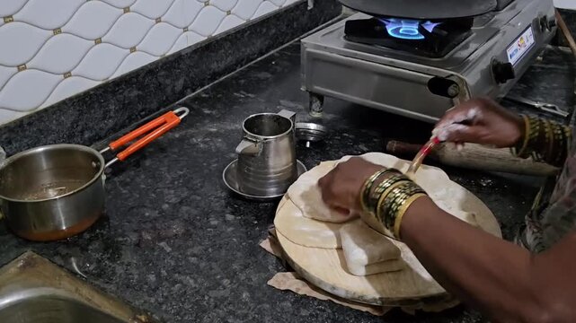 An Indian woman applies oil or ghee and folds dough, creating flaky layers in parathas. Techniques like accordion or square folds trap fat, ensuring soft, multi-layered results when re-rolled and cook