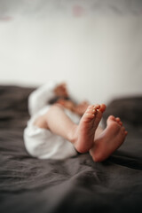Baby feet in bed, newborn baby feet in gray blanket