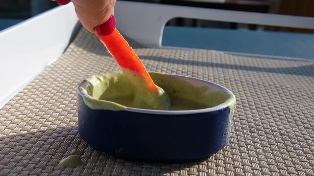 Dipping bell peppers in green sauce on the street in a blue plate, eating vegetables, healthy eating