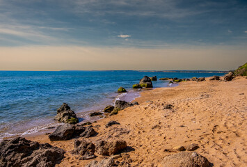 A deserted seashore with sand and rocks.