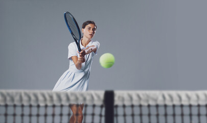 Young Female Tennis Player Hitting Ball on Neutral Background