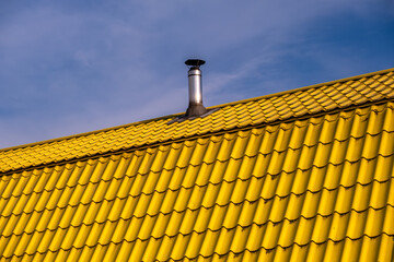 Round small iron chimney on the roof of the house.