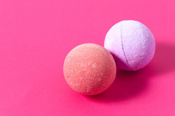 Colorful bath bombs resting on bright pink background