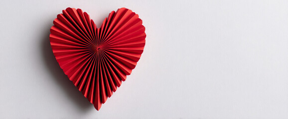 Obraz premium A beautifully crafted red paper heart with intricate folds, set against a clean white background, symbolizing love and affection, perfect for romantic themes and celebrations