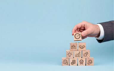 Building Business Goals from Strategic Foundations, Hand places target icon atop pyramid of business concept blocks