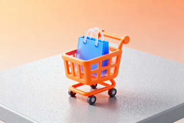 Miniature orange shopping cart with blue bags on a gray surface against a warm gradient background