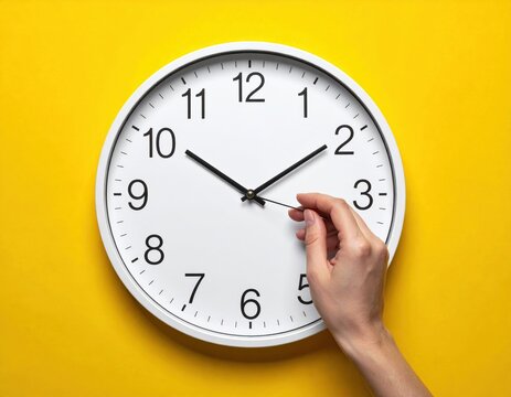 Clock with hand adjusting time on yellow background.