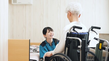 高齢者の移乗介助をするアジア人介護士 © mapo